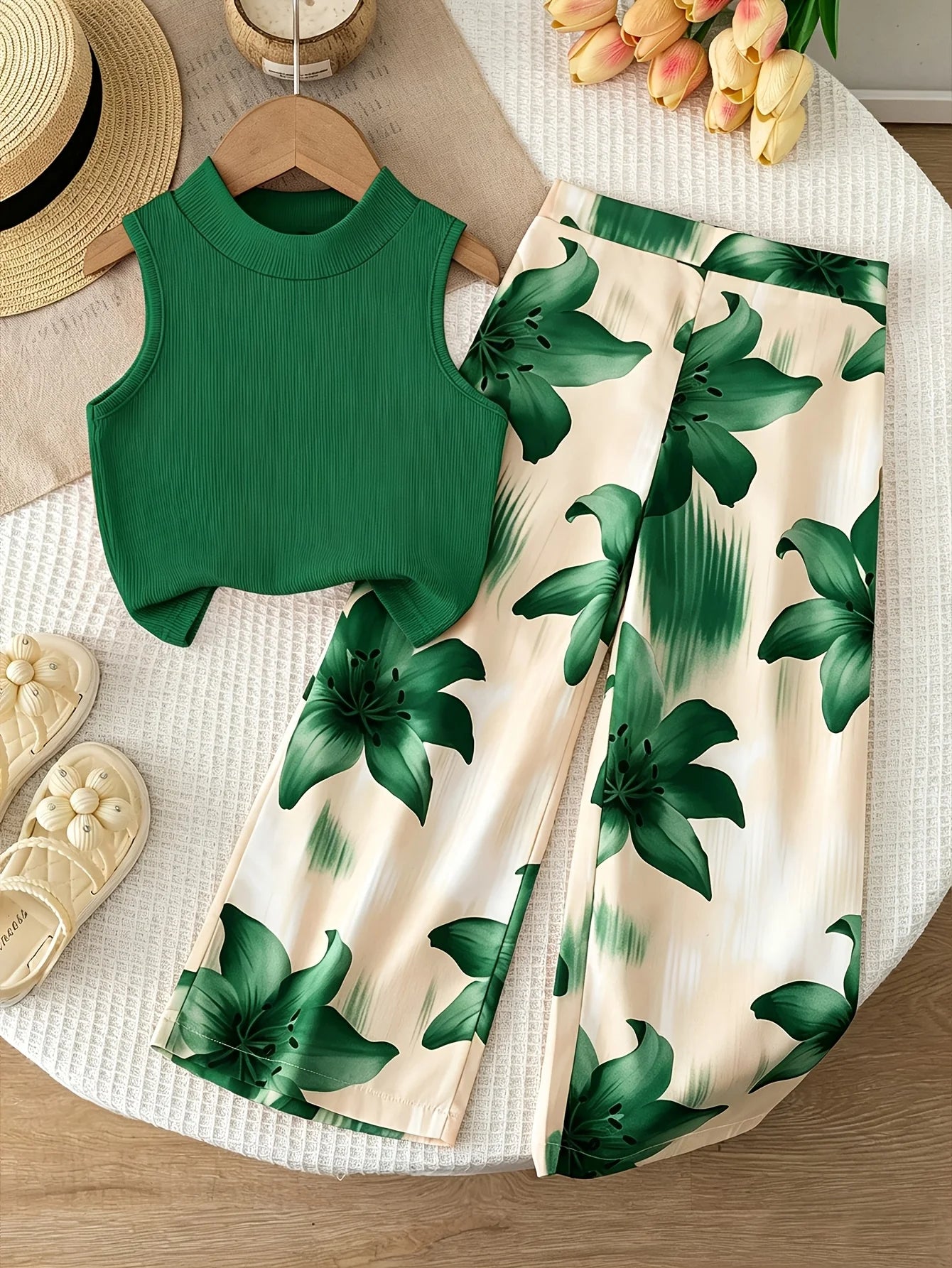 Girls' orange vacation-style two-piece set: a solid-color, ribbed, sleeveless mock-neck crop top paired with lily-print, flowy w